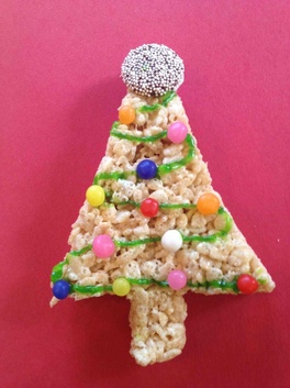 Kids decorating edible Christmas tree treats with frosting